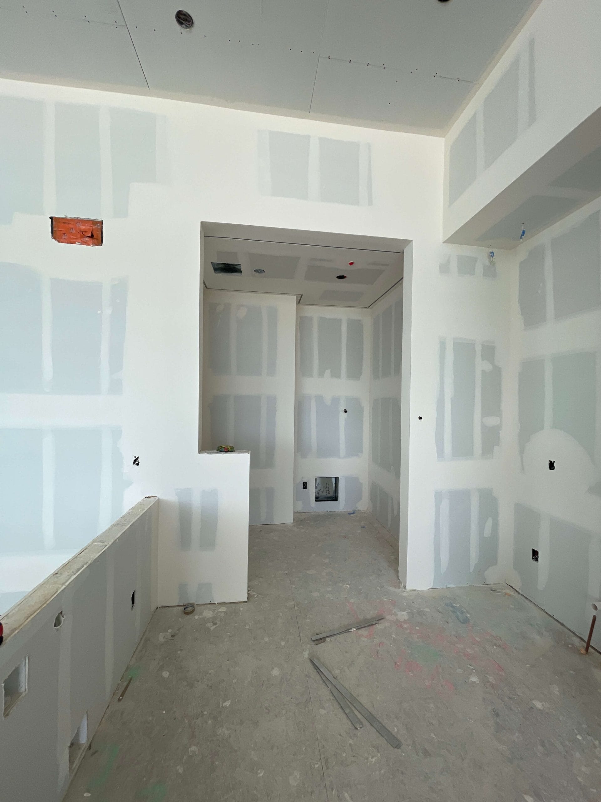 Drywall installation phase of custom wine cellar construction with framed entry opening