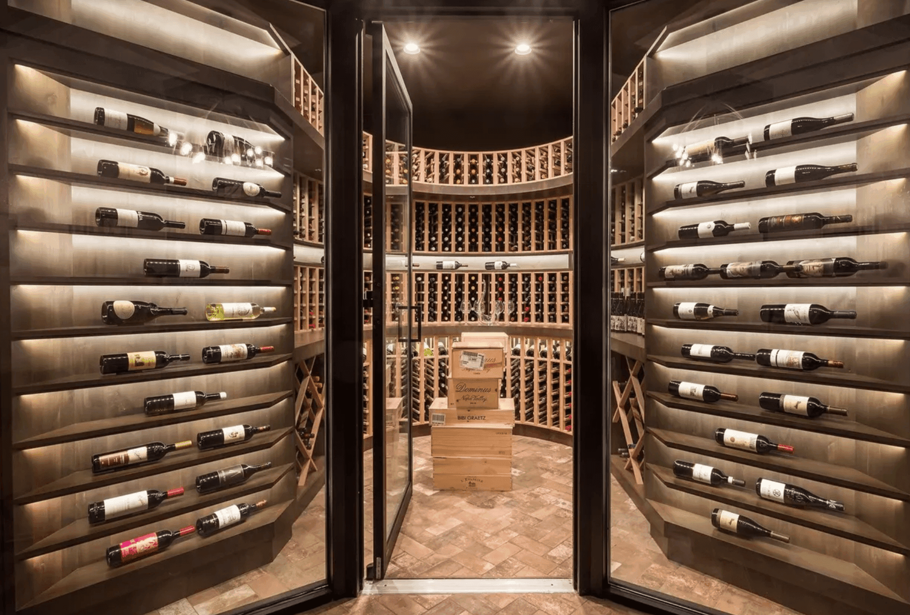 Luxury custom wine cellar with curved wood racking and glass entry doors