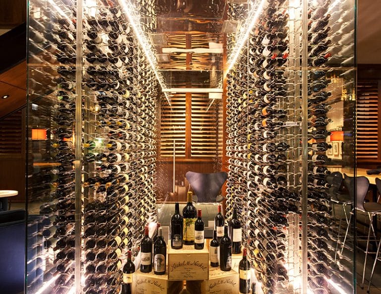Walk-in glass wine room with floor-to-ceiling bottle display, LED lighting, and climate-controlled storage.