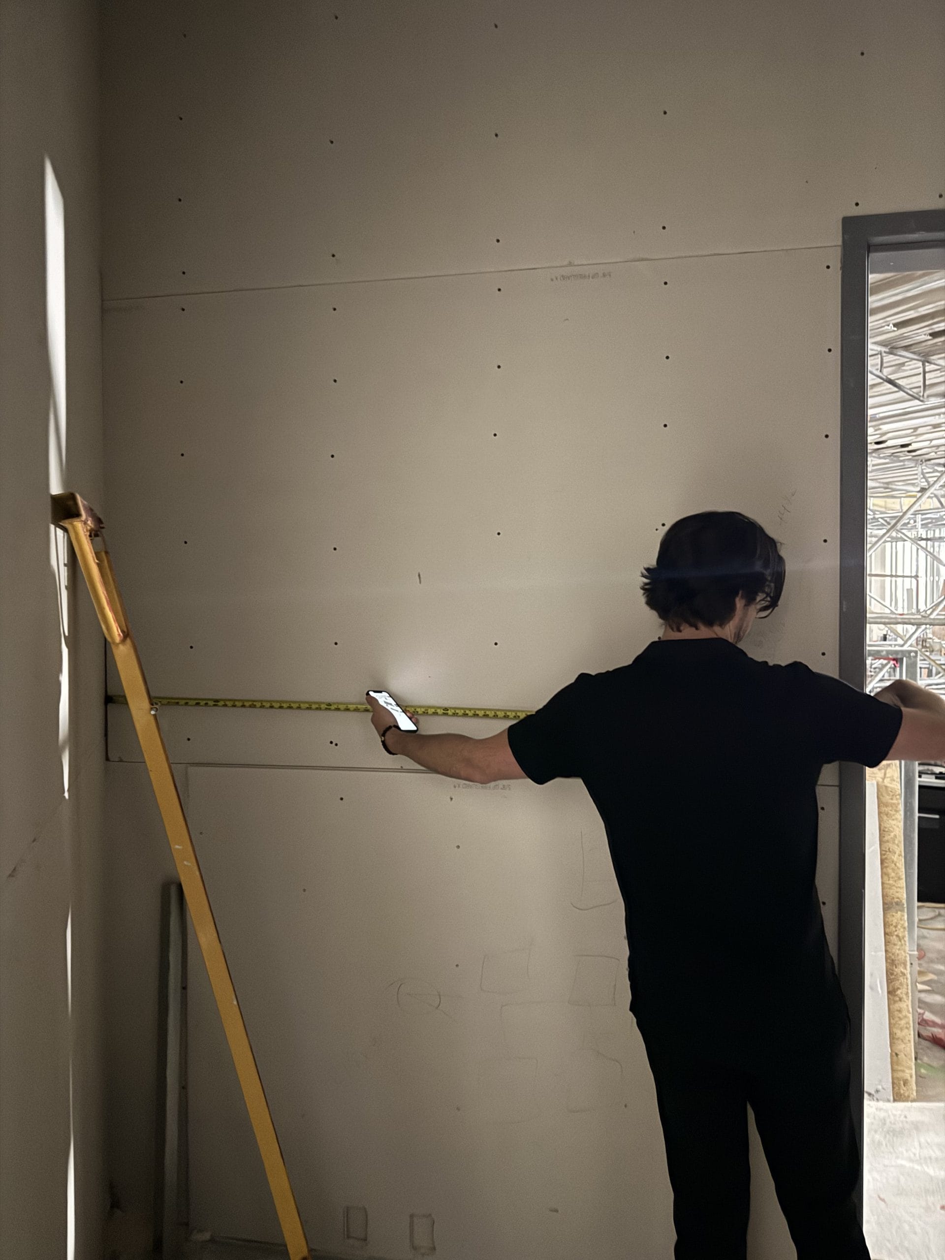 Wine cellar contractor measuring wall framing during custom wine cellar installation
