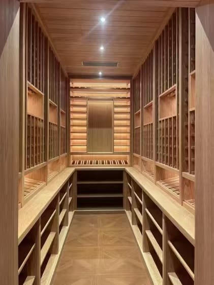 Traditional wood wine cellar design with custom racking, ceiling paneling, and integrated bottle storage.